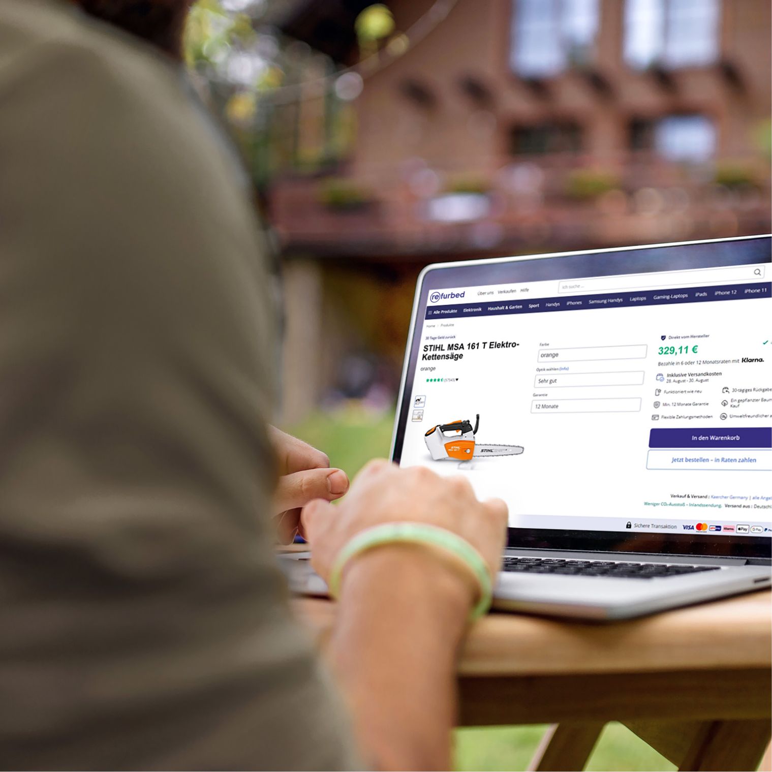Person vor einem Laptop sitzend, der die Refurbed-Website zeigt.